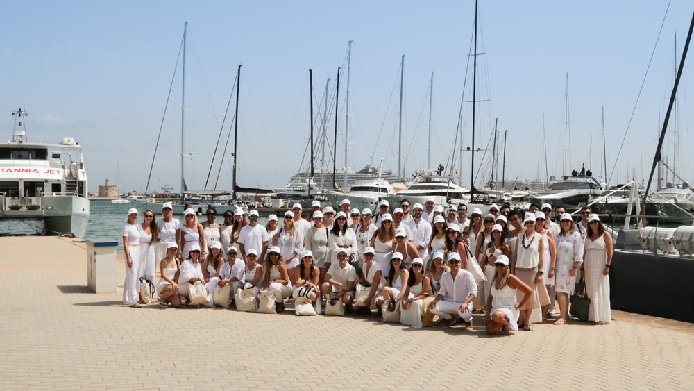 Gruppenbild von Personen am Hafen, die weiß gekleidet sind.