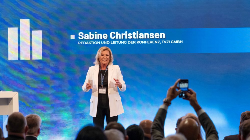 Mit einem Lächeln auf der Bühne – Sabine Christiansen ( (Redaktion und Leitung der Konferenz, TV21 GMBH) spricht mit Charisma und Ausdruckskraft zu den Zuhörern