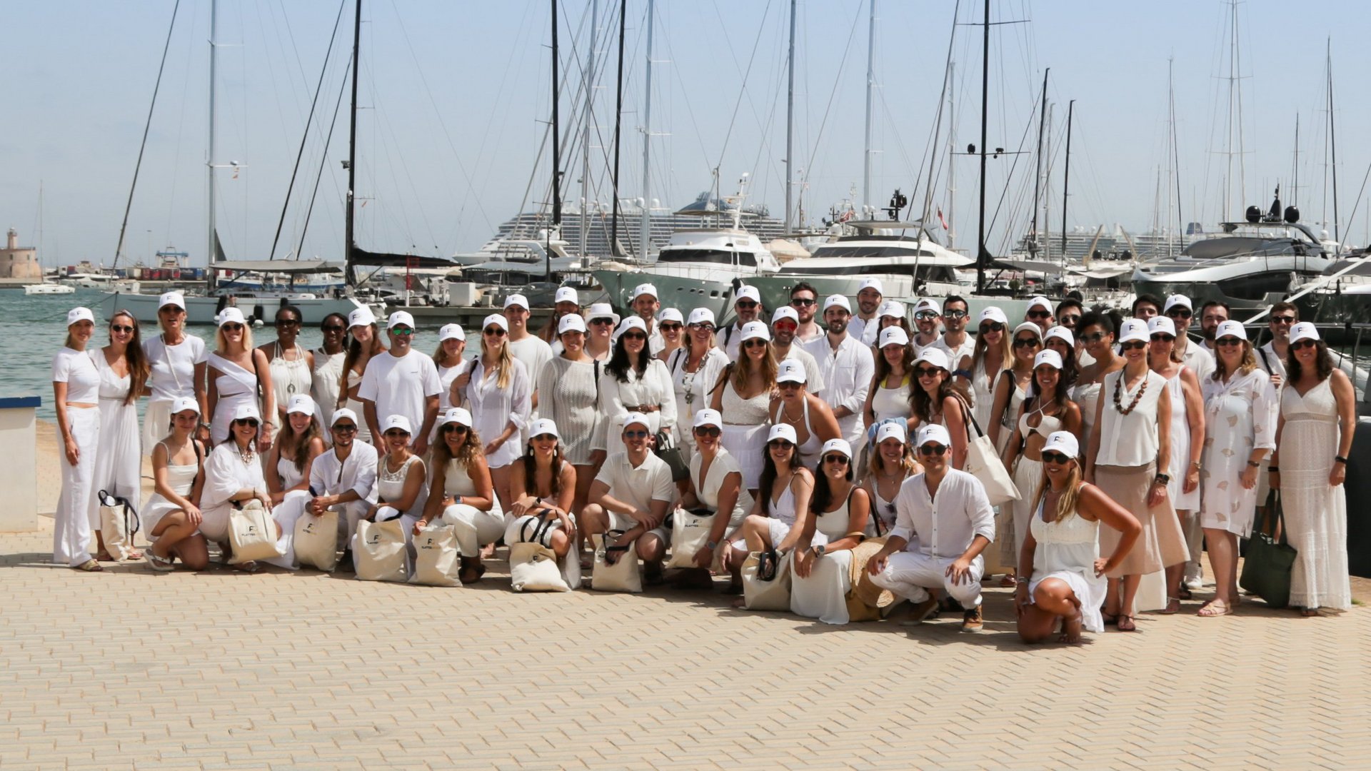 Gruppenfoto vor dem Katamaran im Hafen von Palma, alle Personen sind in weiß gekleidet und lachen in die Kamera